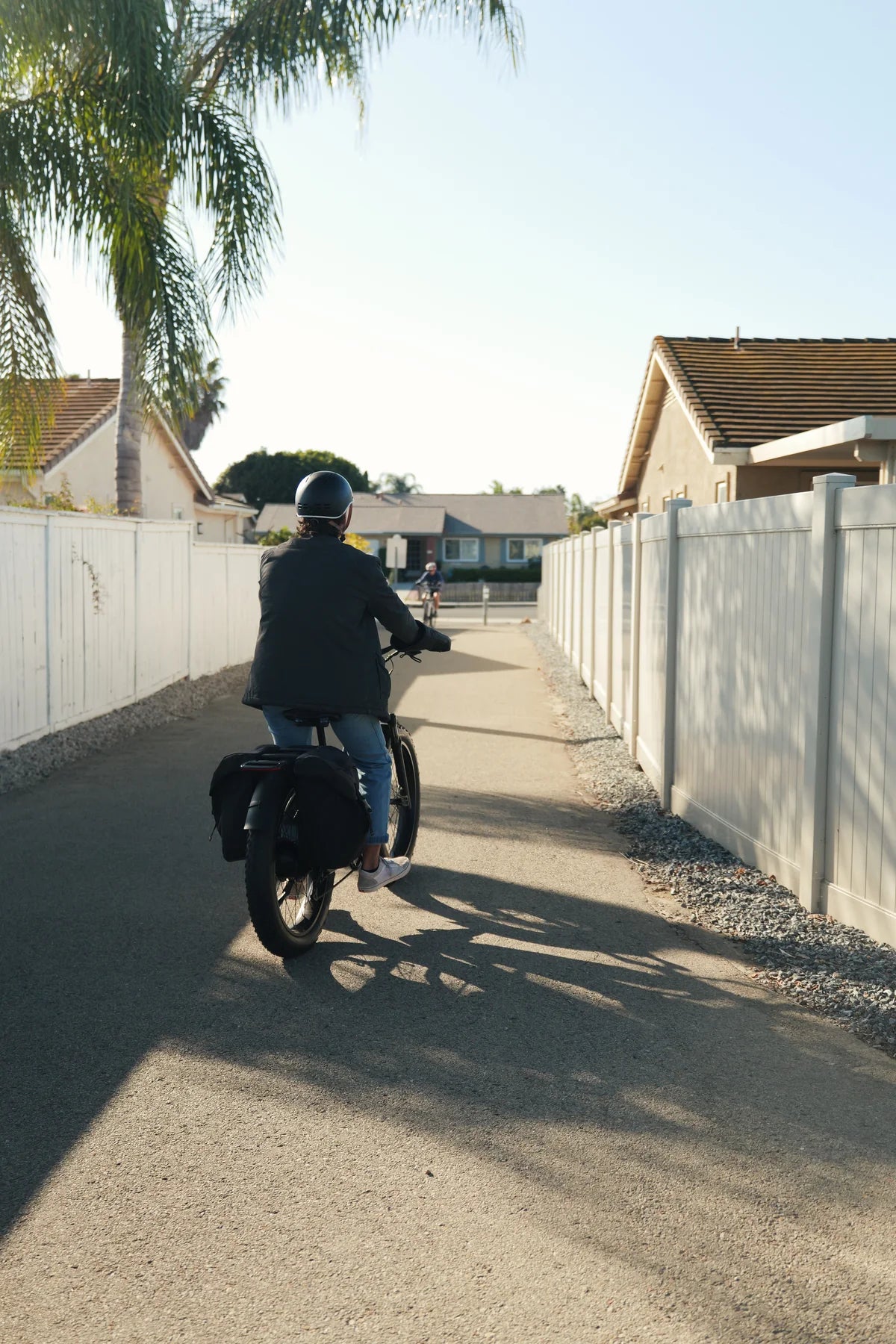Une personne roulant sur un sentier de quartier avec un vélo électrique FavoriteBikes StormX muni de sacoches.
