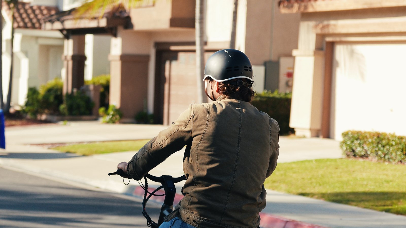 FavoriteBikes rider commuting on a neighborhood street with jacket, helmet, and rear bags.