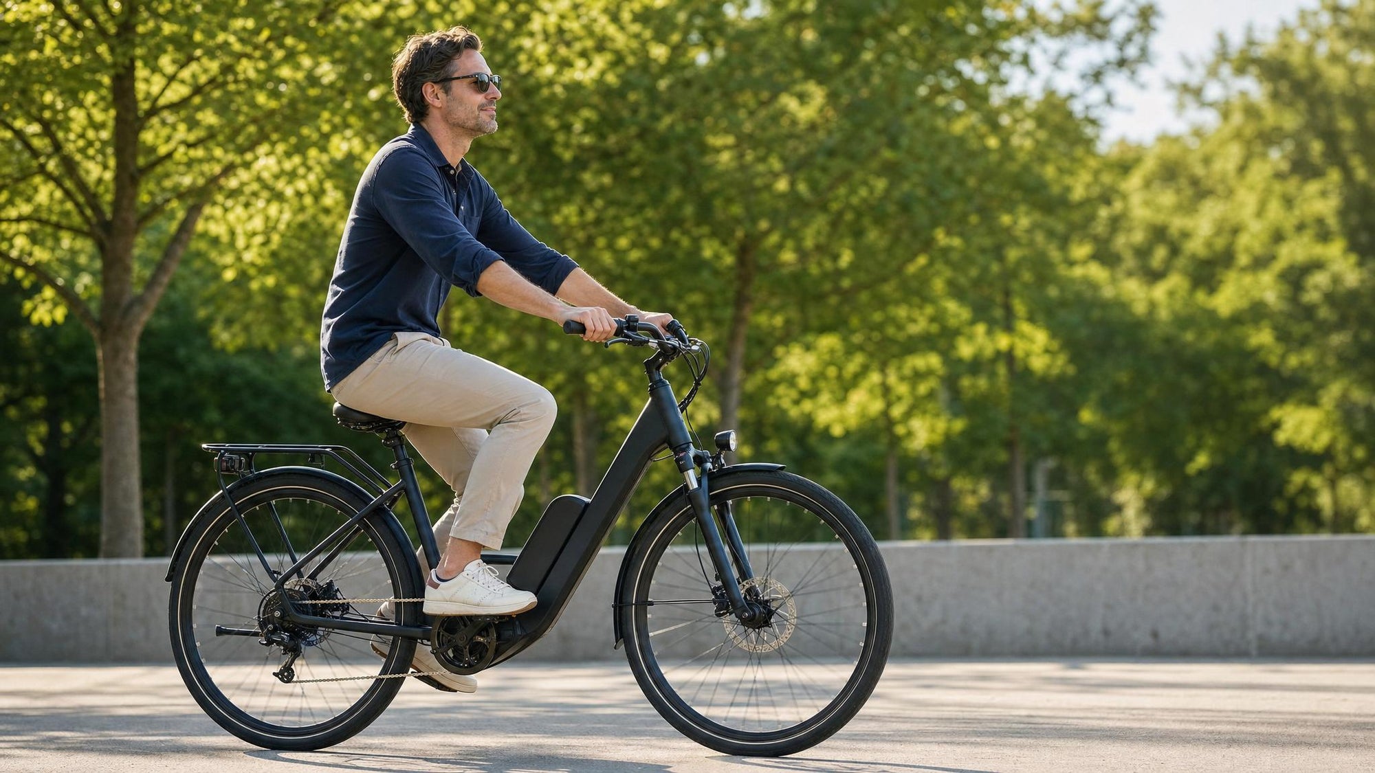 Adult e-bike rider with relaxed ergonomic posture on a sunlit paved bike path, soft elbow bend, dropped shoulders, level hips on a comfortably set saddle, swept-back commuter handlebars at saddle height