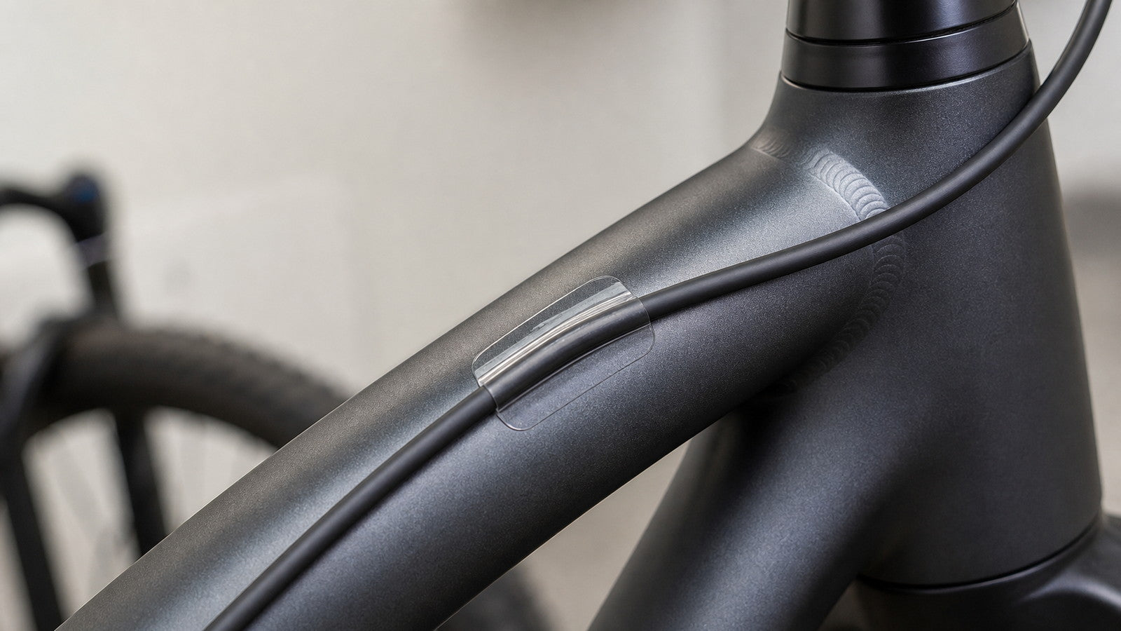 Clear frame protection patch beneath an e-bike cable housing contact point