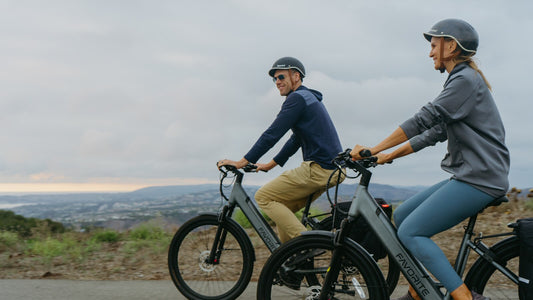 Two helmeted FavoriteBikes riders riding together on a coastal road