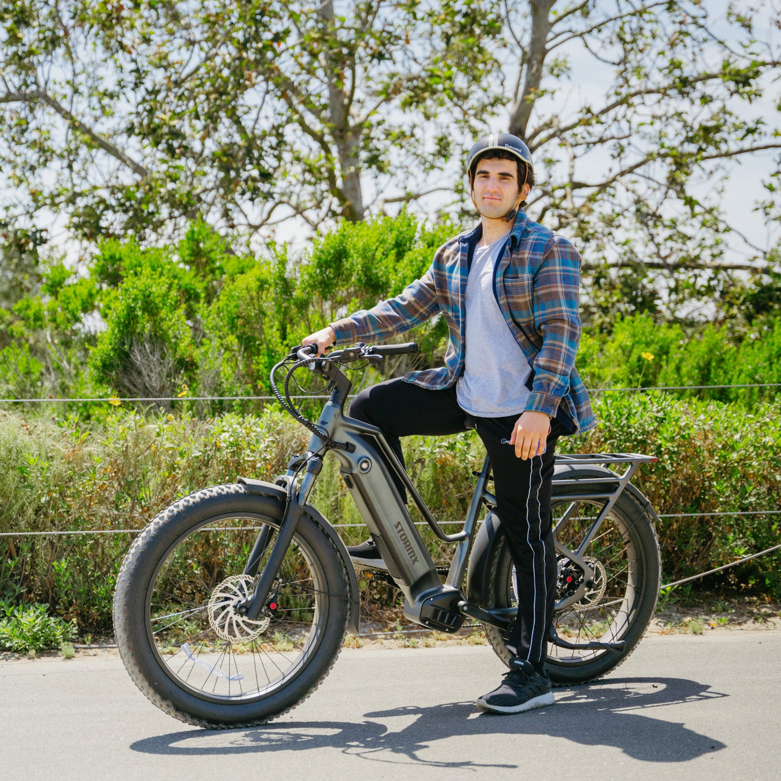 Man posing with Favoritebikes StormX Fat tire Ebike Costco on a paved path, emphasizing its stylish design and electric biking features.