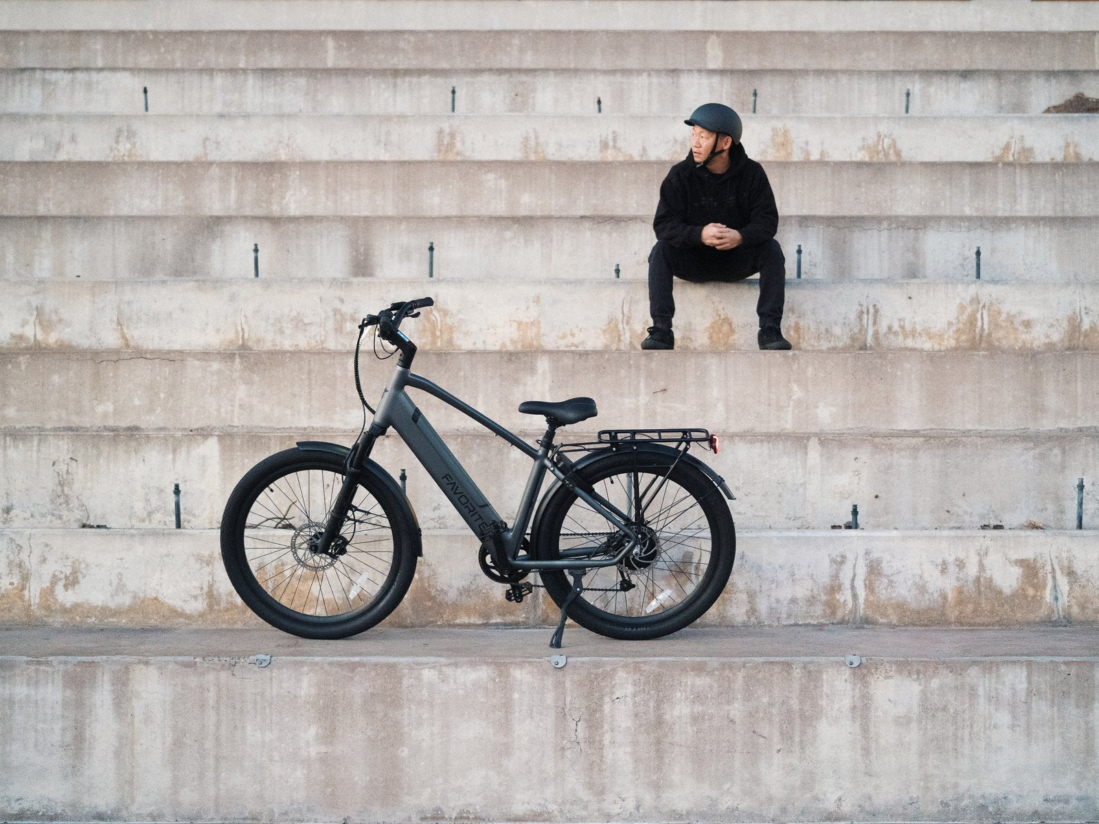 FavoriteBikes Hybrid Pro XR crossover electric bike with a rear rack on concrete steps