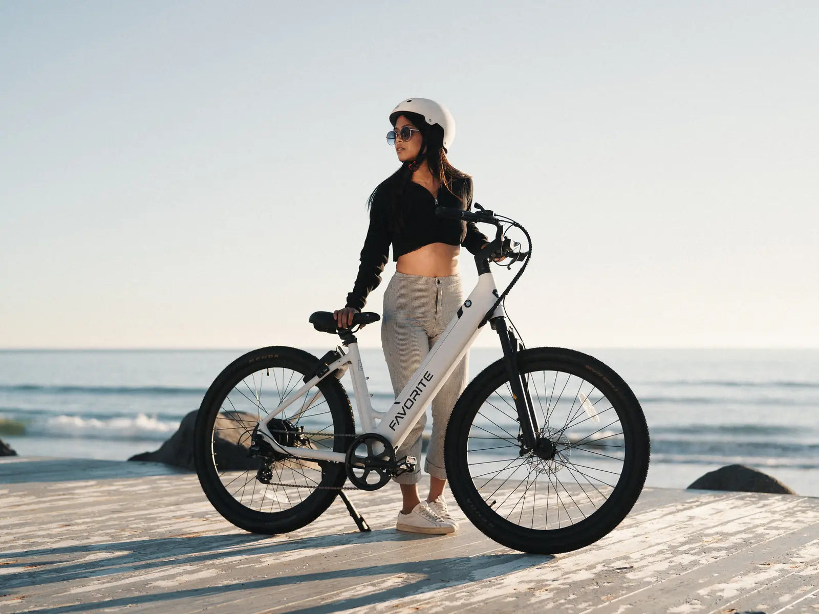 Rider with a white FavoriteBikes Hybrid step-through electric bike by the beach