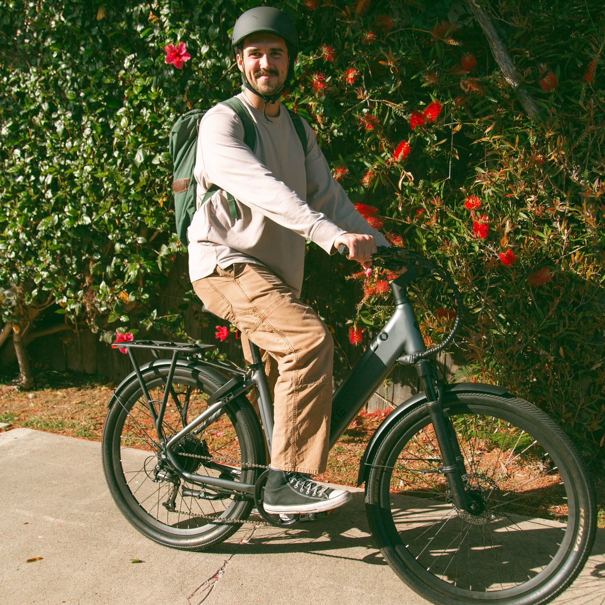 Rider with a FavoriteBikes Hybrid commuter e-bike beside flowering shrubs