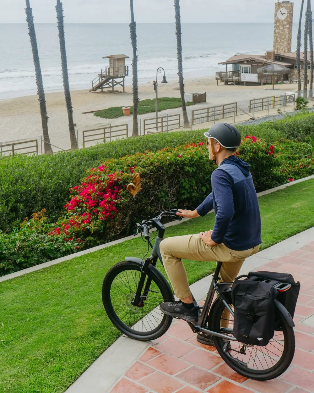 Cycliste FavoriteBikes en trajet quotidien sur une route côtière pavée, avec sacoches arrière