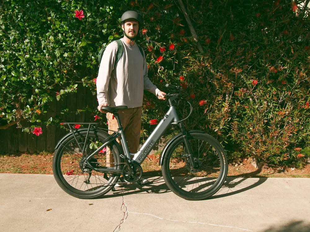 Rider standing beside a FavoriteBikes step-through electric bike on a paved path